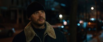 Movie still from “The Drop” (2014), directed by Michaël R. Roskam – A person wearing a jacket and a hat; Close Up shot, Over the shoulder angle