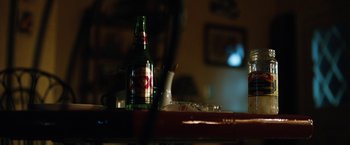 Movie still from “The Drop” (2014), directed by Michaël R. Roskam – A bottle of beer sitting on top of a table; Extreme Close Up shot, High angle