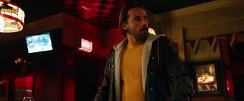 Movie still from “The Drop” (2014), directed by Michaël R. Roskam – A man in a yellow shirt and a black jacket; Medium shot, Low angle