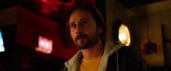 Movie still from “The Drop” (2014), directed by Michaël R. Roskam – A person with a beard looking at the camera; Close Up shot, Over the shoulder angle