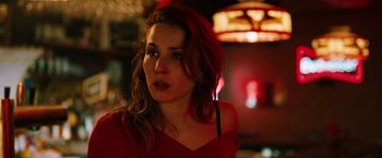 Movie still from “The Drop” (2014), directed by Michaël R. Roskam – A woman in a red top is looking at the camera; Close Up shot, Over the shoulder angle