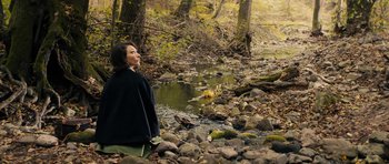 Movie still from “The Duke of Burgundy” (2014), directed by Peter Strickland – A woman standing in the middle of a creek; Wide shot, High angle
