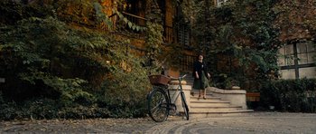Movie still from “The Duke of Burgundy” (2014), directed by Peter Strickland – A woman walking down the stairs with a bicycle; Wide shot, High angle
