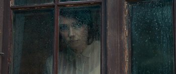 Movie still from “The Duke of Burgundy” (2014), directed by Peter Strickland – A woman looking out of a window through a window; Close Up shot, Over the shoulder angle