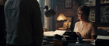 Movie still from “The Duke of Burgundy” (2014), directed by Peter Strickland – Two people sitting at a table with papers and a lamp; Medium shot, Over the shoulder angle