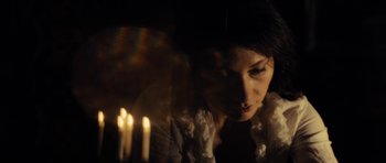 Movie still from “The Duke of Burgundy” (2014), directed by Peter Strickland – A woman looking at a candle in a dark room; Close Up shot, Low angle