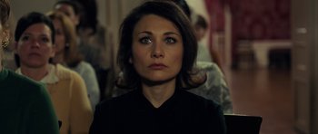 Movie still from “The Duke of Burgundy” (2014), directed by Peter Strickland – A person wearing a black shirt; Close Up shot, Over the shoulder angle