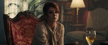 Movie still from “The Duke of Burgundy” (2014), directed by Peter Strickland – A woman sitting on a chair in a living room; Medium shot, Over the shoulder angle