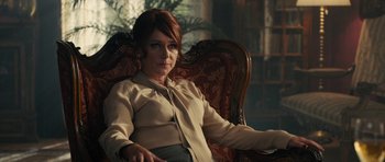 Movie still from “The Duke of Burgundy” (2014), directed by Peter Strickland – A woman sitting in a chair in front of a window; Medium shot, Over the shoulder angle