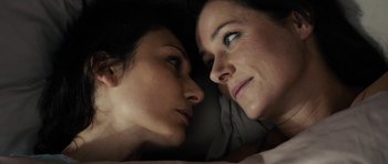 Movie still from “The Duke of Burgundy” (2014), directed by Peter Strickland – A woman and a woman laying in a bed looking into each other's eyes; Close Up shot, Overhead angle