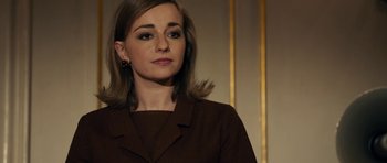 Movie still from “The Duke of Burgundy” (2014), directed by Peter Strickland – A woman in a brown jacket looking to her left; Close Up shot, Over the shoulder angle