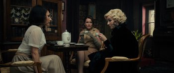 Movie still from “The Duke of Burgundy” (2014), directed by Peter Strickland – A group of women sitting at a table drinking tea; Medium shot, Over the shoulder angle