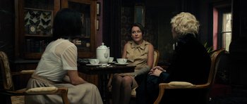 Movie still from “The Duke of Burgundy” (2014), directed by Peter Strickland – A woman sitting at a table with a tea pot; Medium shot, Over the shoulder angle