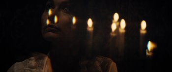 Movie still from “The Duke of Burgundy” (2014), directed by Peter Strickland – A woman is looking out of a window at candles; Extreme Close Up shot, Over the shoulder angle