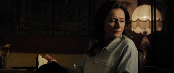 Movie still from “The Duke of Burgundy” (2014), directed by Peter Strickland – A woman in a striped shirt is looking down; Medium shot, Over the shoulder angle