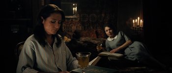 Movie still from “The Duke of Burgundy” (2014), directed by Peter Strickland – Two women sitting at a table with a glass of wine; Medium shot, Over the shoulder angle