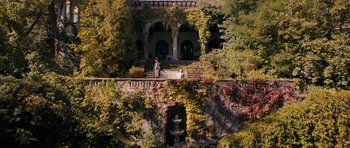 Movie still from “The Duke of Burgundy” (2014), directed by Peter Strickland – Two people are standing on the steps of a house; Extreme Wide shot, High angle