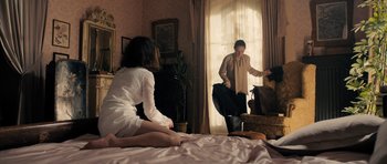 Movie still from “The Duke of Burgundy” (2014), directed by Peter Strickland – A woman sitting on a bed in front of a window; Wide shot, High angle