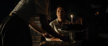 Movie still from “The Duke of Burgundy” (2014), directed by Peter Strickland – A woman sitting in front of a birthday cake; Medium shot, Over the shoulder angle