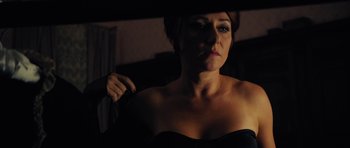 Movie still from “The Duke of Burgundy” (2014), directed by Peter Strickland – A woman in a strapless dress holding onto a curtain; Close Up shot, Over the shoulder angle