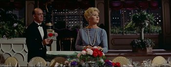 Movie still from “The Eddy Duchin Story” (1956), directed by George Sidney – A woman sitting at a table with a bouquet of flowers in front of her; Medium shot, Low angle