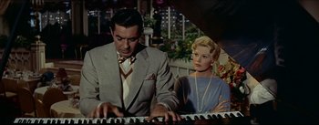 Movie still from “The Eddy Duchin Story” (1956), directed by George Sidney – A man and a woman are playing the piano; Medium shot, Low angle