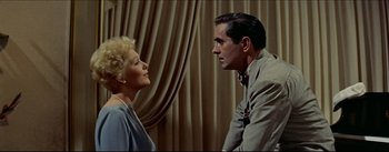 Movie still from “The Eddy Duchin Story” (1956), directed by George Sidney – A man and a woman standing next to each other in a room; Medium shot, Over the shoulder angle
