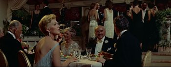 Movie still from “The Eddy Duchin Story” (1956), directed by George Sidney – A group of people sitting at a dinner table; Medium shot, Over the shoulder angle