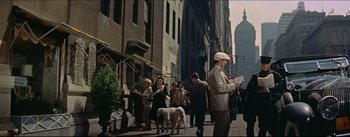 Movie still from “The Eddy Duchin Story” (1956), directed by George Sidney – A group of people walking down a street with buildings in the background; Wide shot, High angle