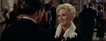 Movie still from “The Eddy Duchin Story” (1956), directed by George Sidney – A woman in a fur collar talking to a man in a black suit; Close Up shot, Over the shoulder angle