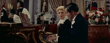 Movie still from “The Eddy Duchin Story” (1956), directed by George Sidney – A man and a woman playing a piano in a living room; Medium shot, Low angle