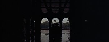 Movie still from “The Eddy Duchin Story” (1956), directed by George Sidney – Three people standing under an archway in the rain; Extreme Wide shot, Low angle