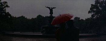 Movie still from “The Eddy Duchin Story” (1956), directed by George Sidney – Two people with an umbrella in front of a statue; Wide shot, Low angle