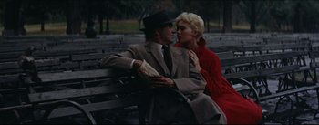 Movie still from “The Eddy Duchin Story” (1956), directed by George Sidney – A man and a woman sitting on a park bench; Medium shot, High angle