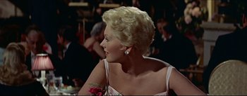 Movie still from “The Eddy Duchin Story” (1956), directed by George Sidney – A woman with blonde curly hair wearing a white dress; Close Up shot, Over the shoulder angle