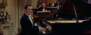 Movie still from “The Eddy Duchin Story” (1956), directed by George Sidney – A man sitting at a piano in front of a group of people; Medium shot, High angle