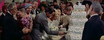 Movie still from “The Eddy Duchin Story” (1956), directed by George Sidney – A man and a woman cutting a wedding cake; Medium shot, High angle