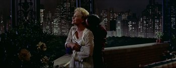 Movie still from “The Eddy Duchin Story” (1956), directed by George Sidney – A woman standing next to a man on a balcony; Medium shot, High angle