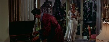 Movie still from “The Eddy Duchin Story” (1956), directed by George Sidney – A man and a woman standing next to each other in a room; Wide shot, Over the shoulder angle