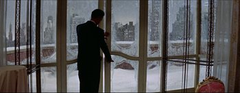 Movie still from “The Eddy Duchin Story” (1956), directed by George Sidney – A man standing in front of a window in a room; Wide shot, High angle