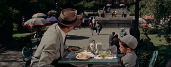 Movie still from “The Eddy Duchin Story” (1956), directed by George Sidney – A man sitting at a table with a plate of food on top of it; Medium shot, High angle