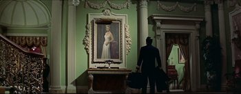 Movie still from “The Eddy Duchin Story” (1956), directed by George Sidney – A man standing in front of a painting of a woman; Wide shot, Low angle