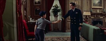 Movie still from “The Eddy Duchin Story” (1956), directed by George Sidney – A man in a uniform shaking hands with a boy in a uniform; Medium shot, Over the shoulder angle