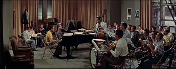 Movie still from “The Eddy Duchin Story” (1956), directed by George Sidney – A group of men sitting around a table playing musical instruments; Wide shot, High angle