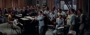 Movie still from “The Eddy Duchin Story” (1956), directed by George Sidney – A group of men playing musical instruments in front of a crowd; Wide shot, High angle
