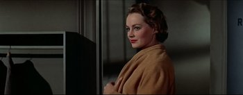 Movie still from “The Eddy Duchin Story” (1956), directed by George Sidney – A woman in a brown robe standing in front of a mirror; Close Up shot, Low angle