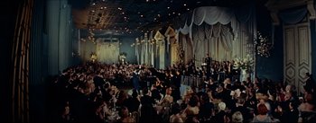 Movie still from “The Eddy Duchin Story” (1956), directed by George Sidney – A large crowd of people in a room; Extreme Wide shot, High angle