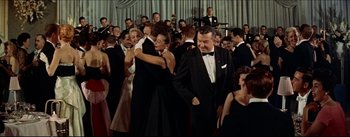 Movie still from “The Eddy Duchin Story” (1956), directed by George Sidney – A group of people in black suits and ties dancing together; Wide shot, Low angle