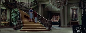 Movie still from “The Eddy Duchin Story” (1956), directed by George Sidney – A man and a woman standing on the stairs of a house; Wide shot, Low angle