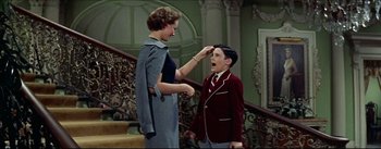 Movie still from “The Eddy Duchin Story” (1956), directed by George Sidney – An older woman and a young boy in front of a stair case; Medium shot, Over the shoulder angle